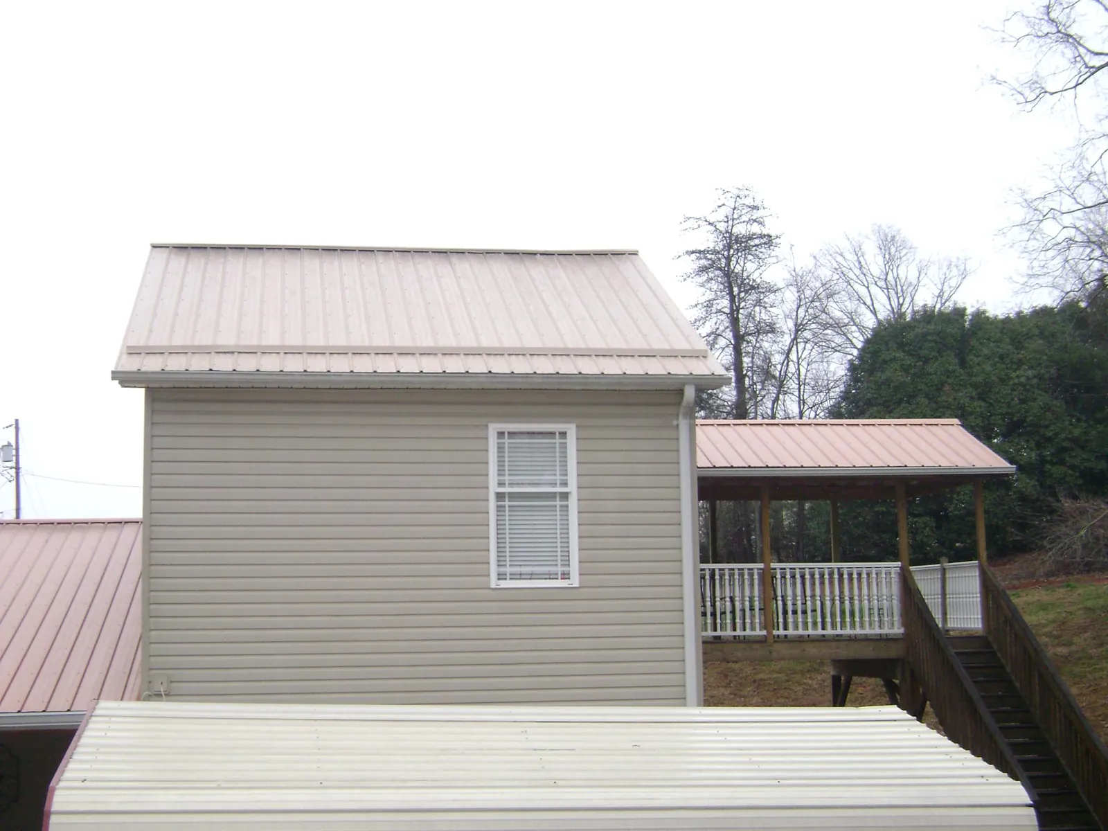 Tan metal roofs on a two story addition and attached porch, from a Roof Replacement job in Bladensburg