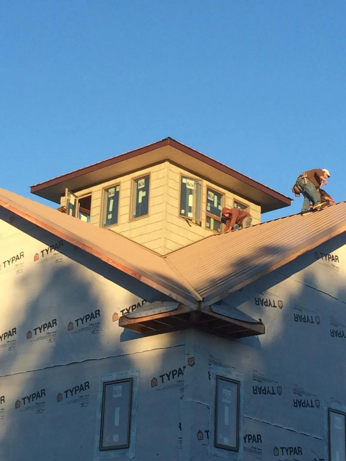 Roofers working around a rooftop cupola on a new metal roof at sunset — Roof Waterproofing in Bladensburg by Roofing Brothers